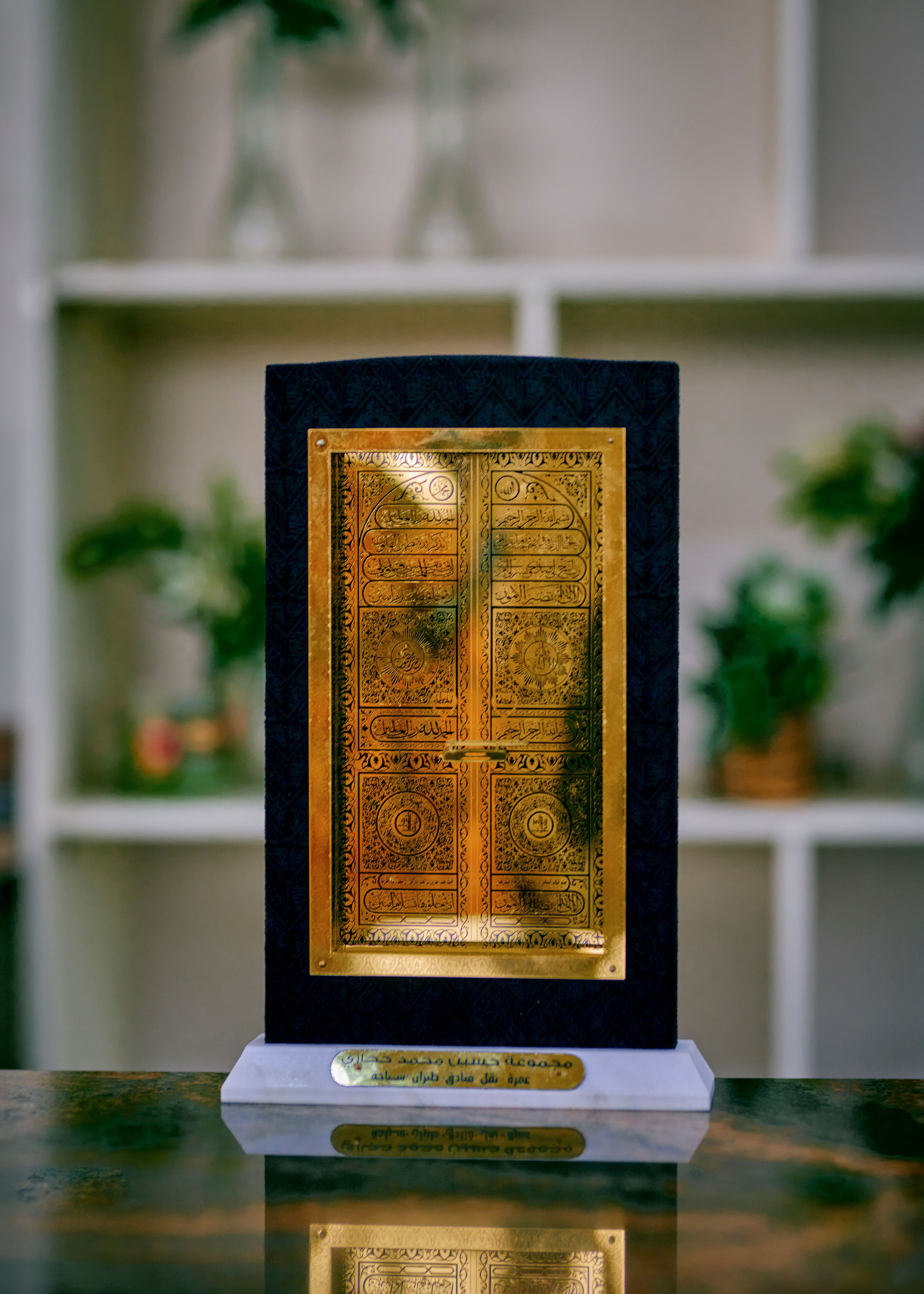 A detailed gold ornamental plaque on a stand against a blurred interior background, perfect for decor inspiration.