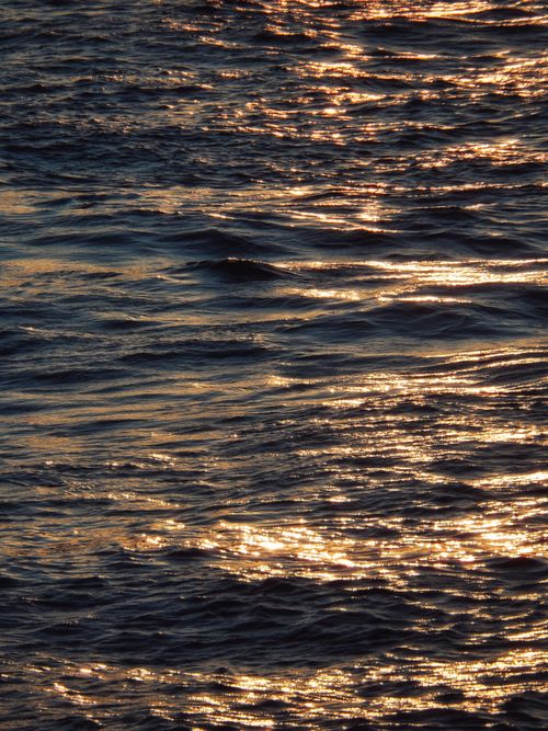 Free Sparkling sunlight reflecting off ocean waves creating a serene and beautiful scene. Stock Photo