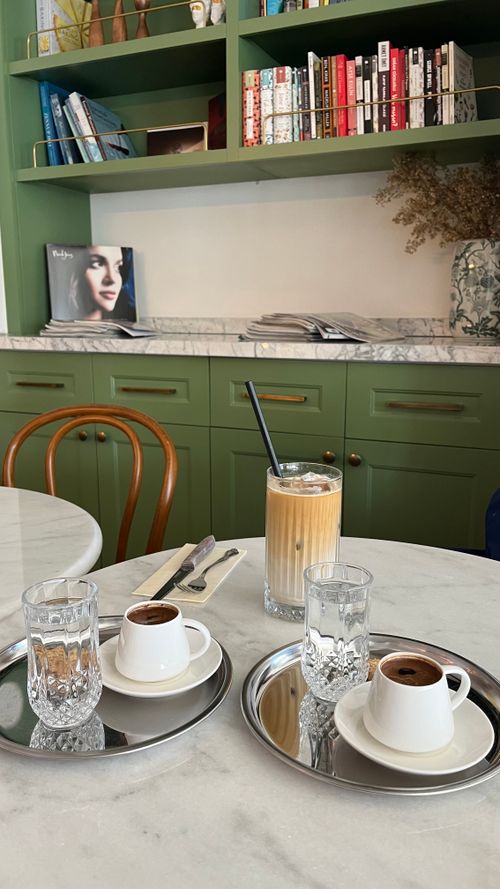 Free Inviting cafe scene with coffee cups and iced beverage on marble table, surrounded by books. Stock Photo