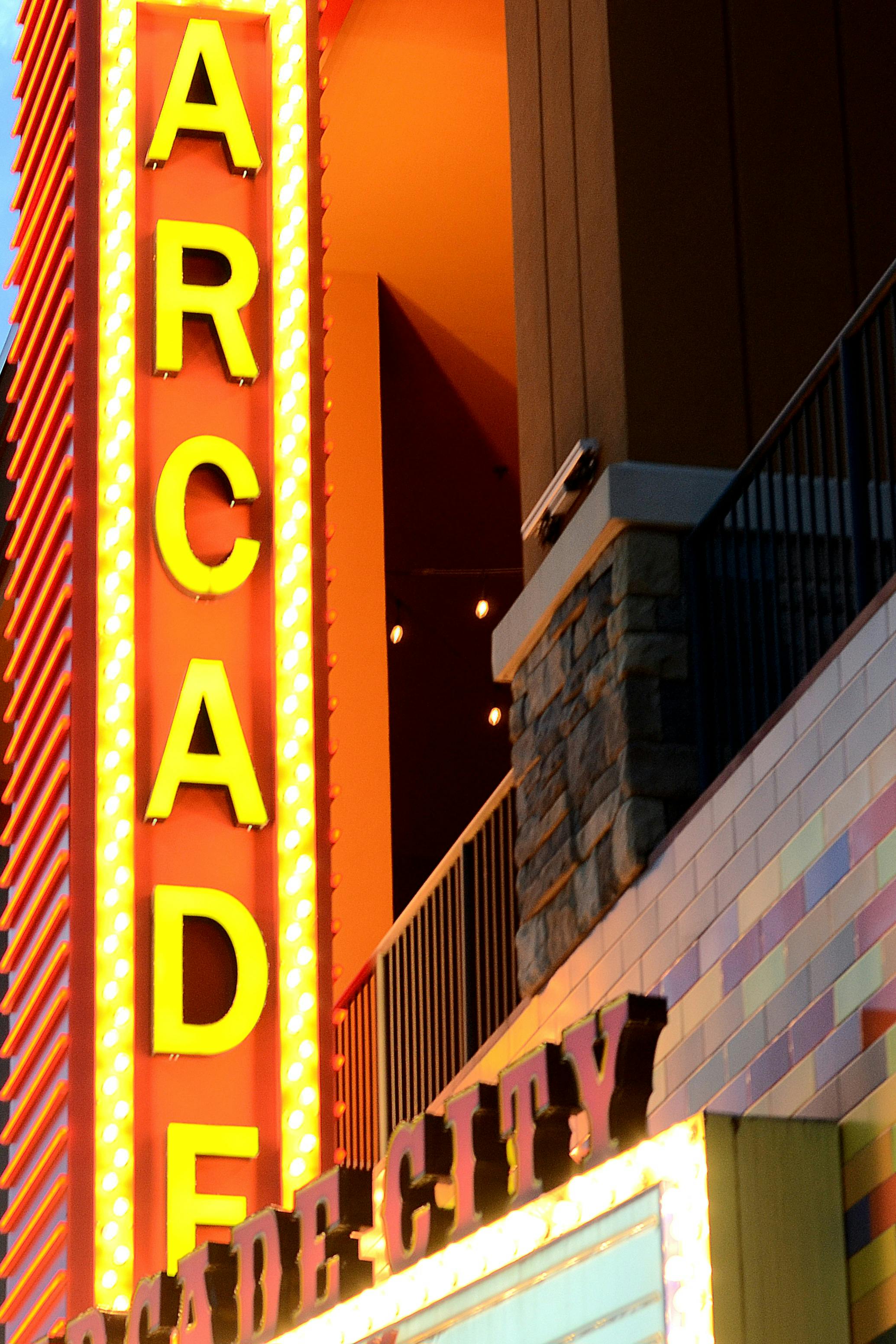 Gratuit Reclame vibrante cu neon luminează intrarea unei arcade la amurg, creând o atmosferă urbană plină de viață. Fotografie de stoc