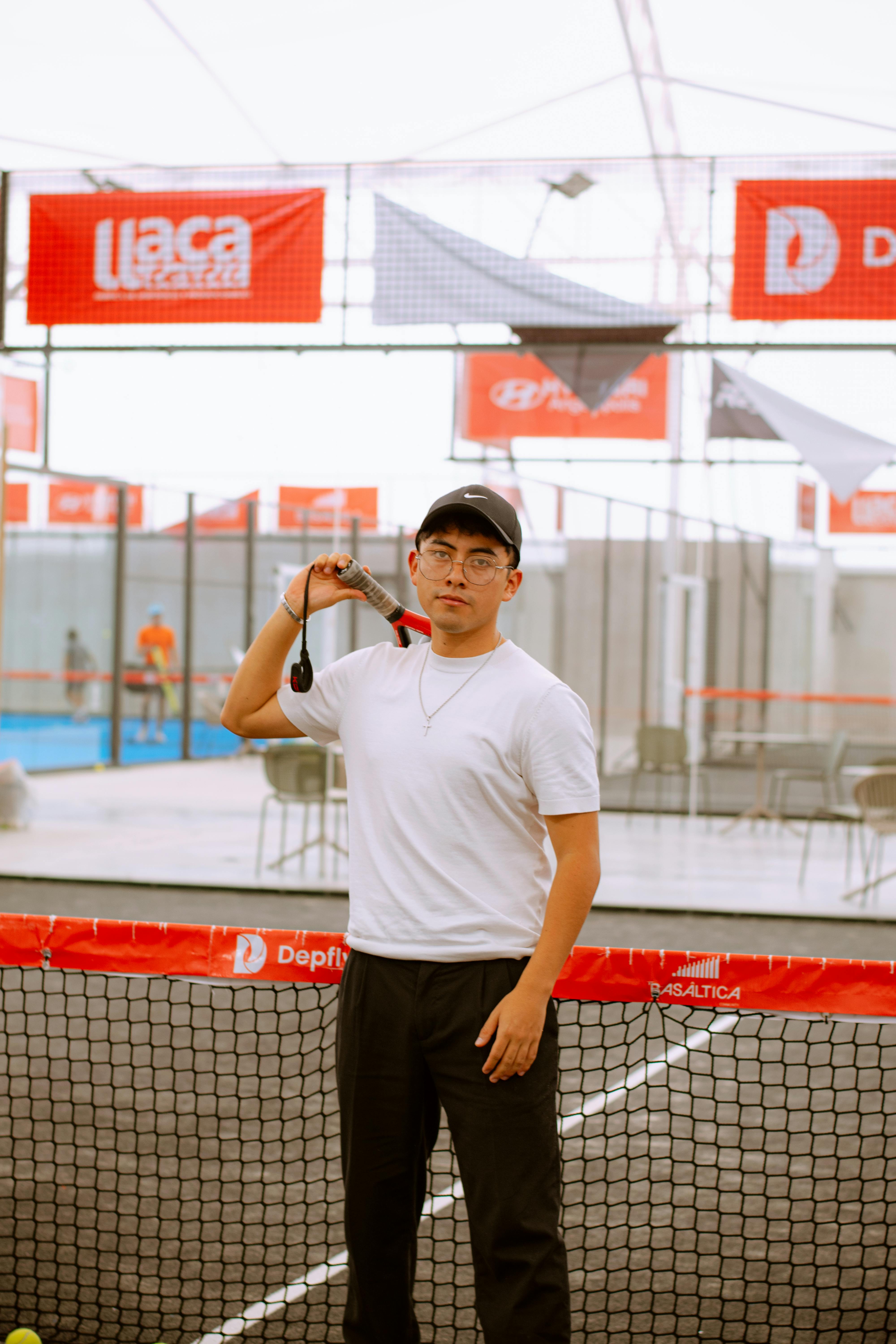 Young man in casual attire holding a tennis racket on an indoor court in Puebla, Mexico.