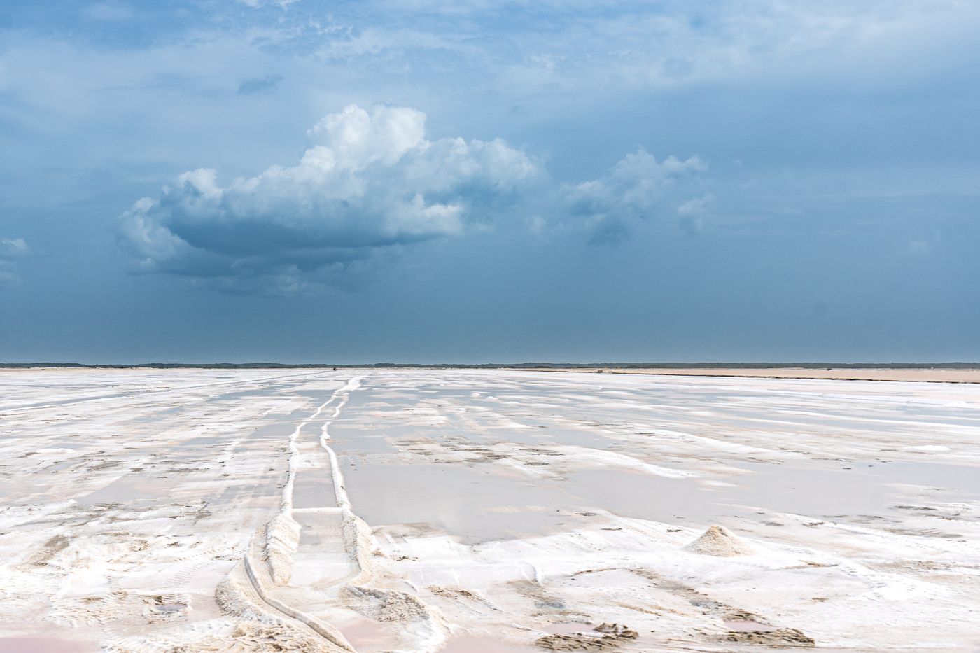 A vast, flat white salt pan stretching to the horizon under a blue sky