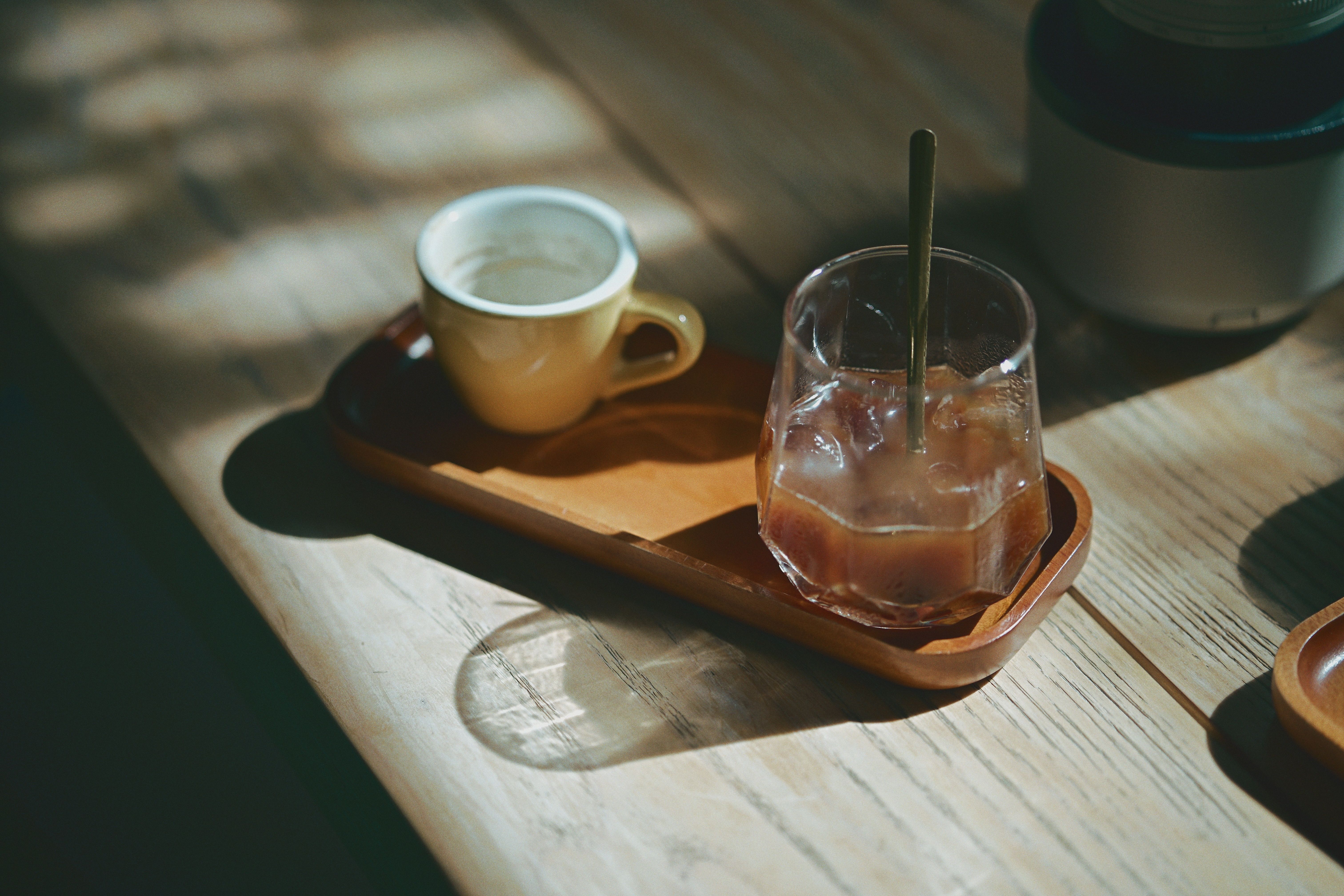 木製のテーブルの上にビンテージのコーヒーカップとアイスドリンクが置かれた居心地の良いシーン。
