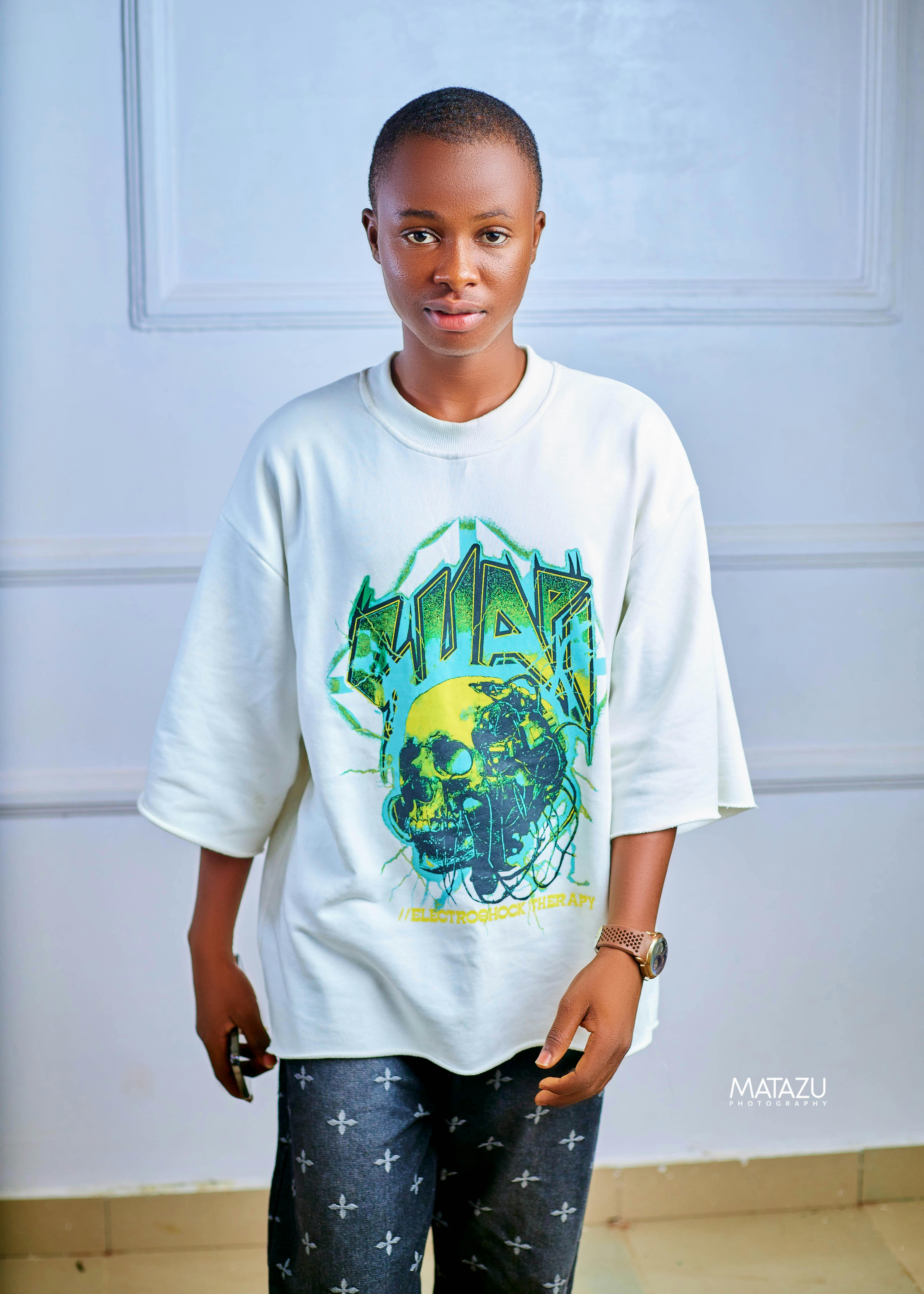Stylish young adult in graphic t-shirt posing indoors with a modern look.