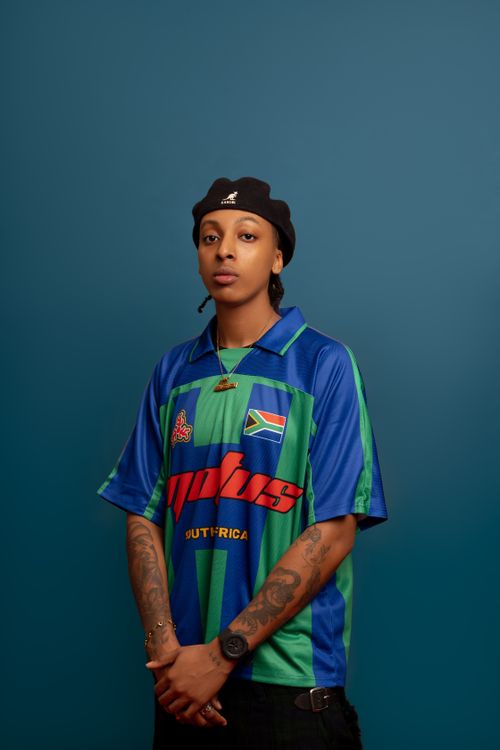 Free Fashionable individual wearing a South African sports jersey against a teal background. Stock Photo