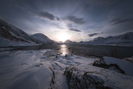 A breathtaking view of snowy mountains and a river during sunrise, capturing the serene winter beauty.
