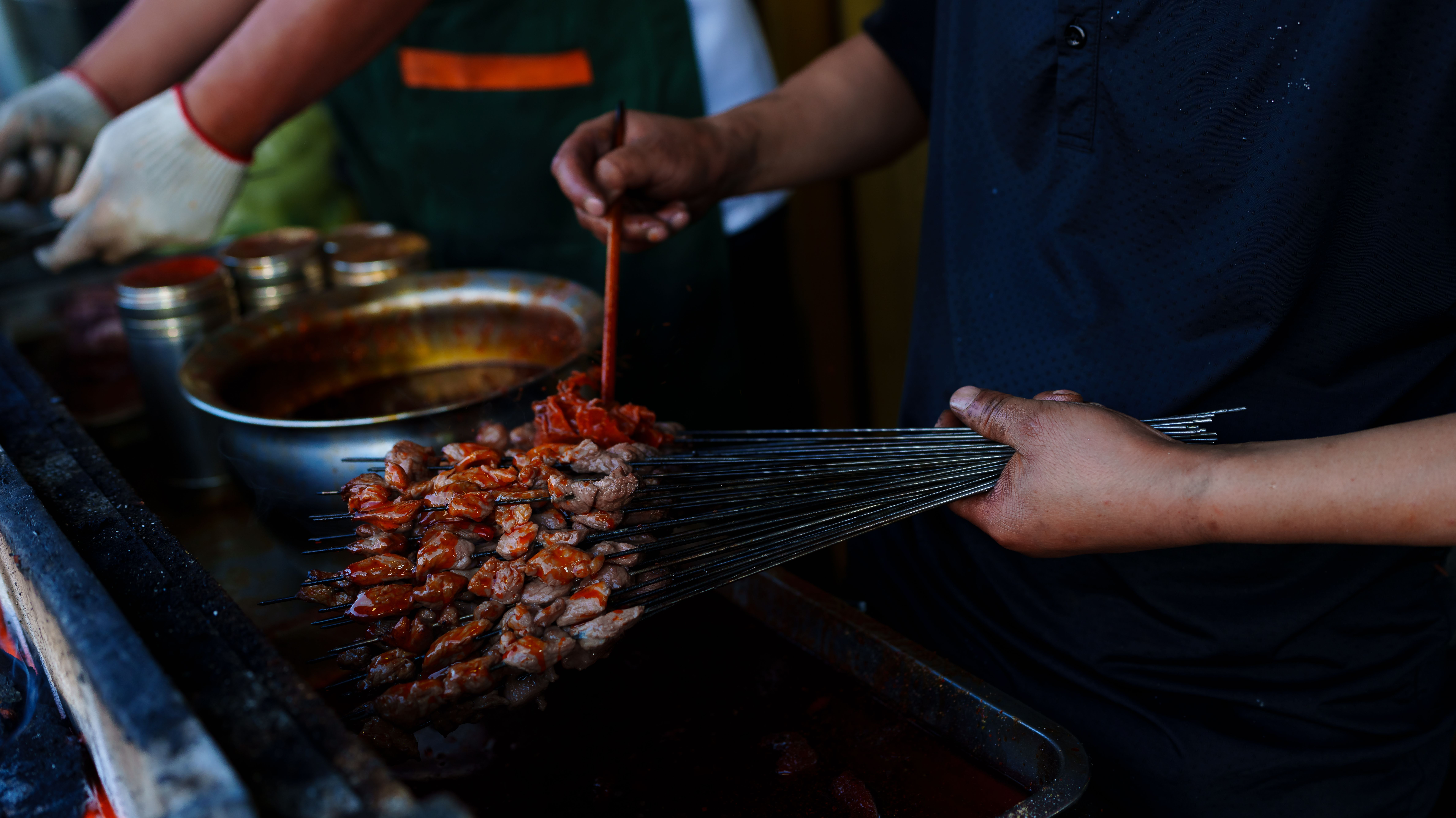 A street vendor preparing traditional grilled skewers in Haibei, Qinghai, capturing vibrant cultural cuisine.