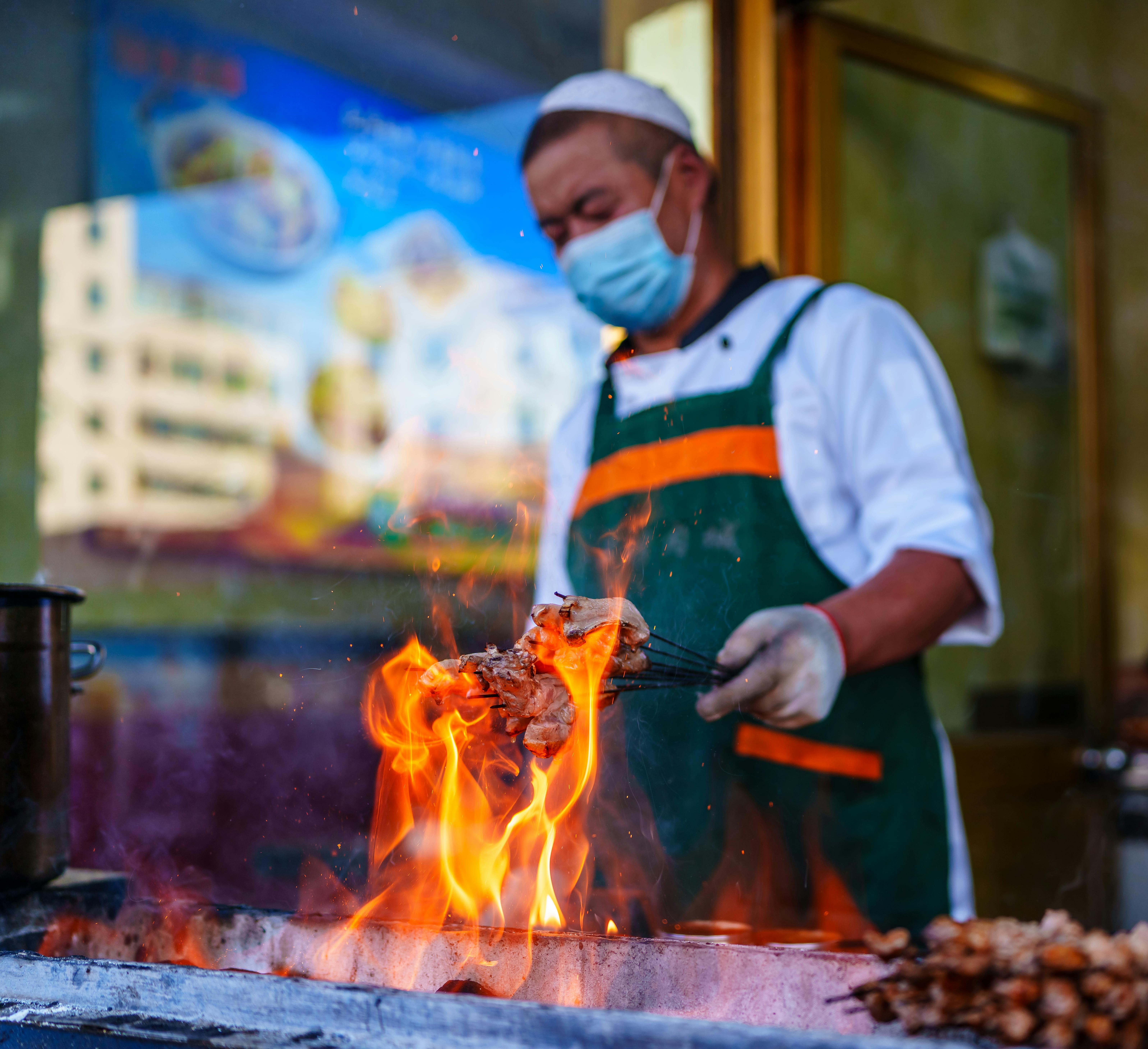A street food vendor grills meat skewers outdoors in Qinghai, China, showcasing local culinary traditions.