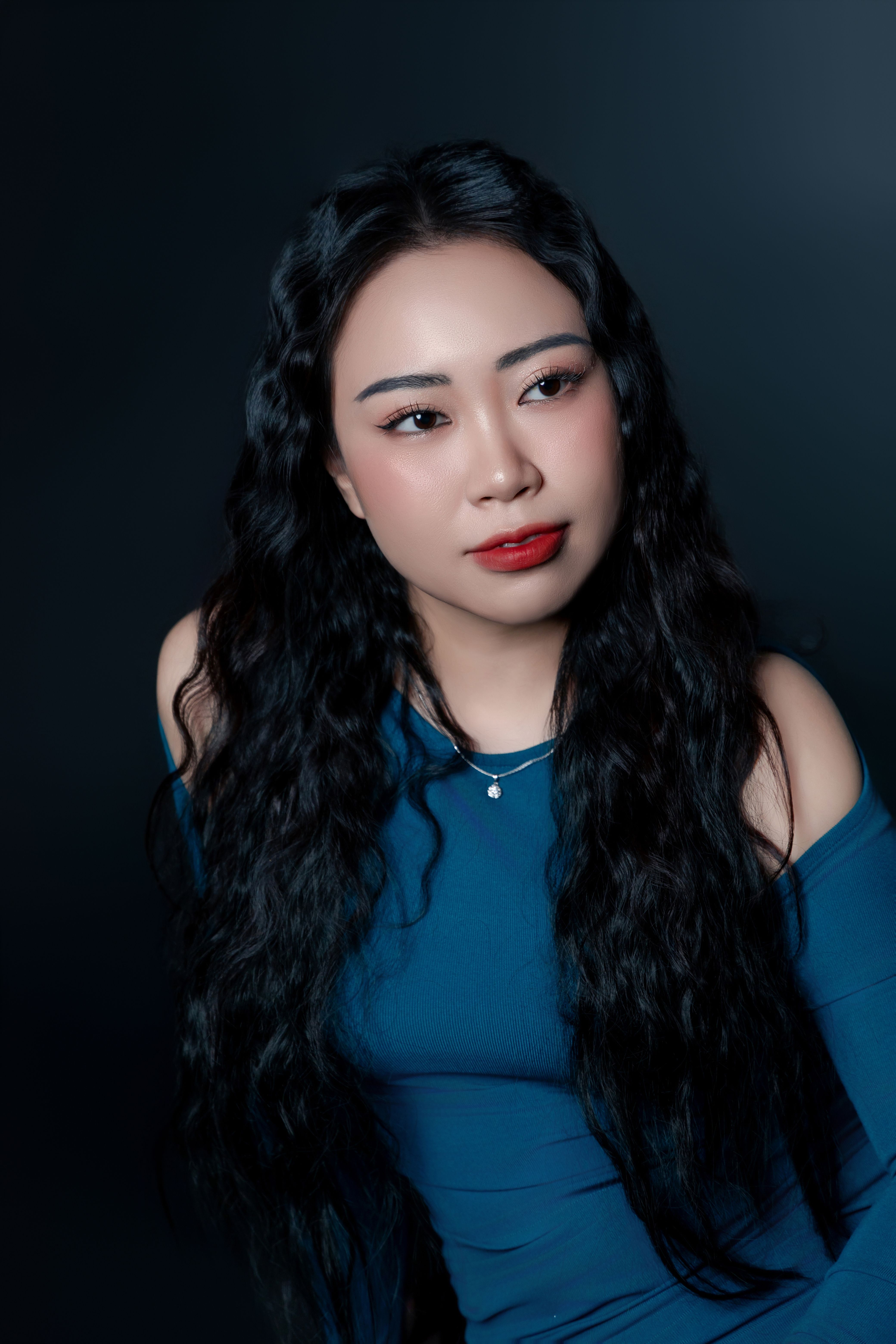 Charming portrait of an Asian woman with long black hair in a blue dress.