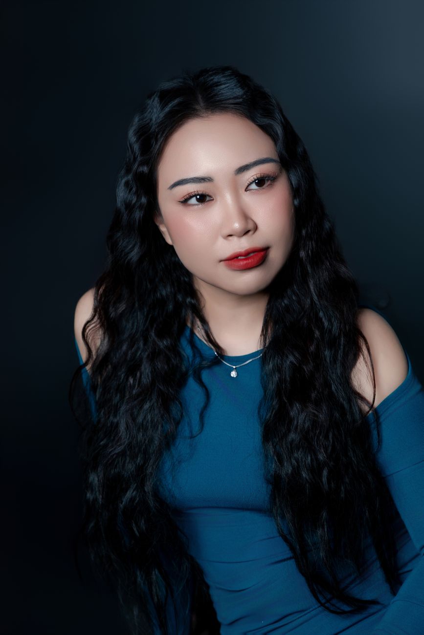 Charming portrait of an Asian woman with long black hair in a blue dress.