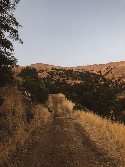 Free Scenic dirt path winds through a dry mountainous landscape under a clear sky. Stock Photo