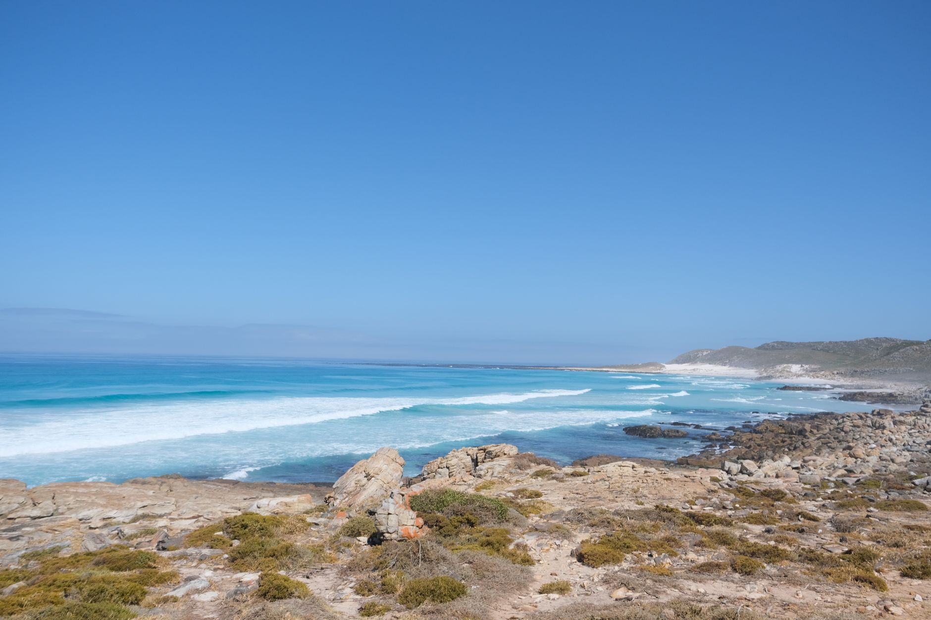 Vast coastal view showcasing the rugged beauty of Cape Town's shoreline under a clear blue sky.
