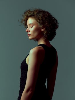 A serene portrait of a woman with curly hair, showcasing elegance and beauty in soft lighting.