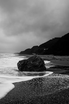 Black and white photo of Şile coastline with dramatic clouds and a rocky beach.