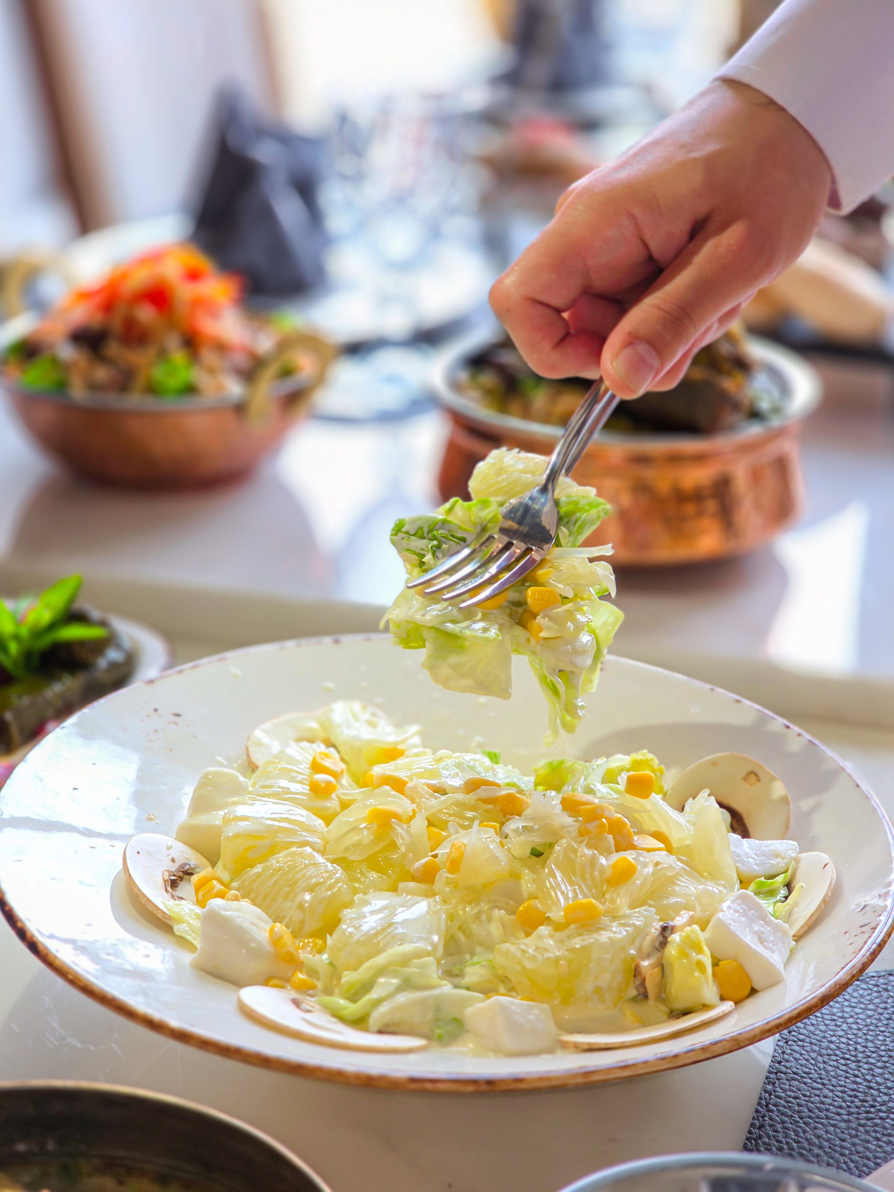 A crisp Caesar salad with lettuce and corn being served on a bright, sunny day.