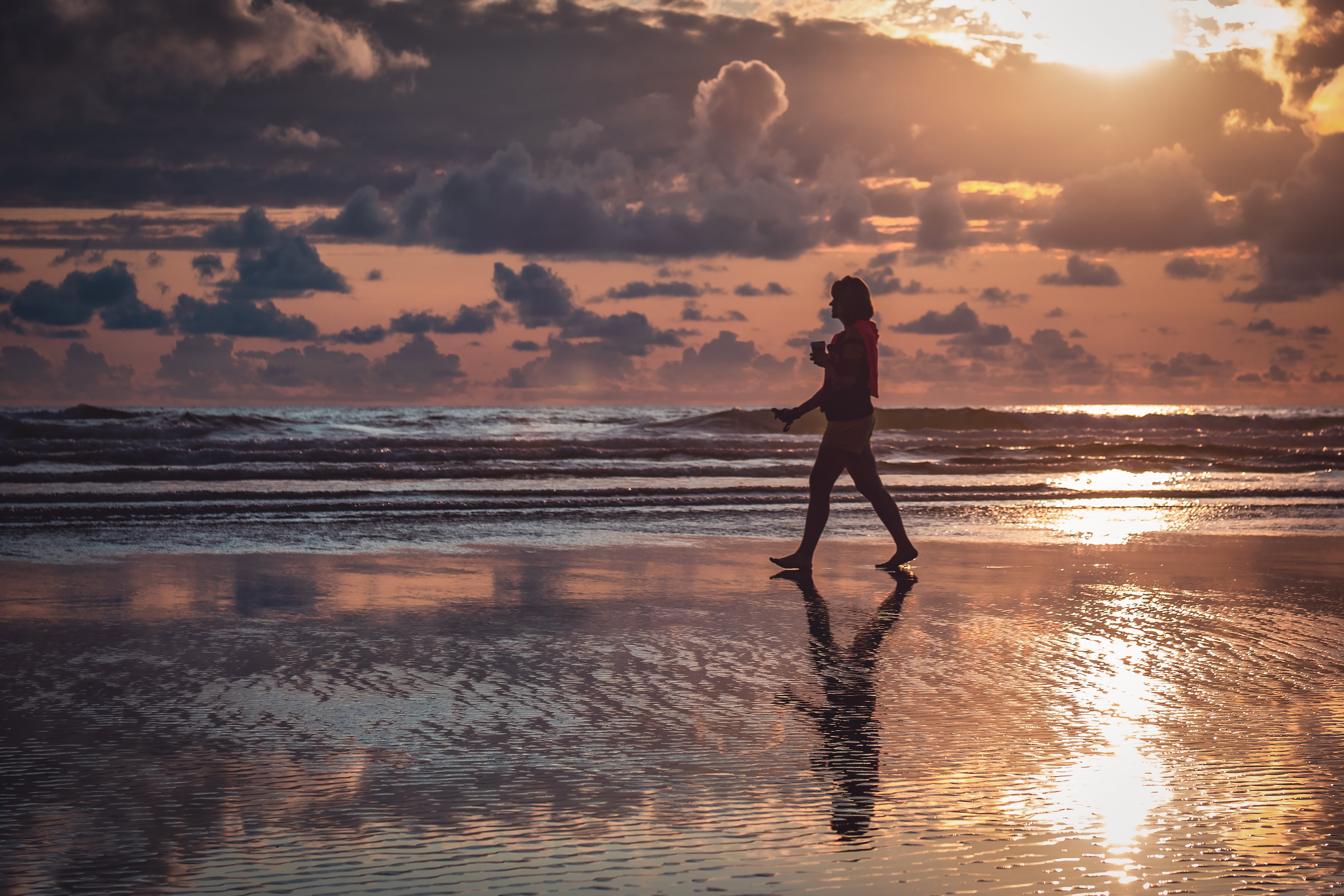 silhouette of walking person on seashore