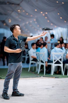 A man skillfully operates a drone at an indoor gathering, showcasing advanced technology.
