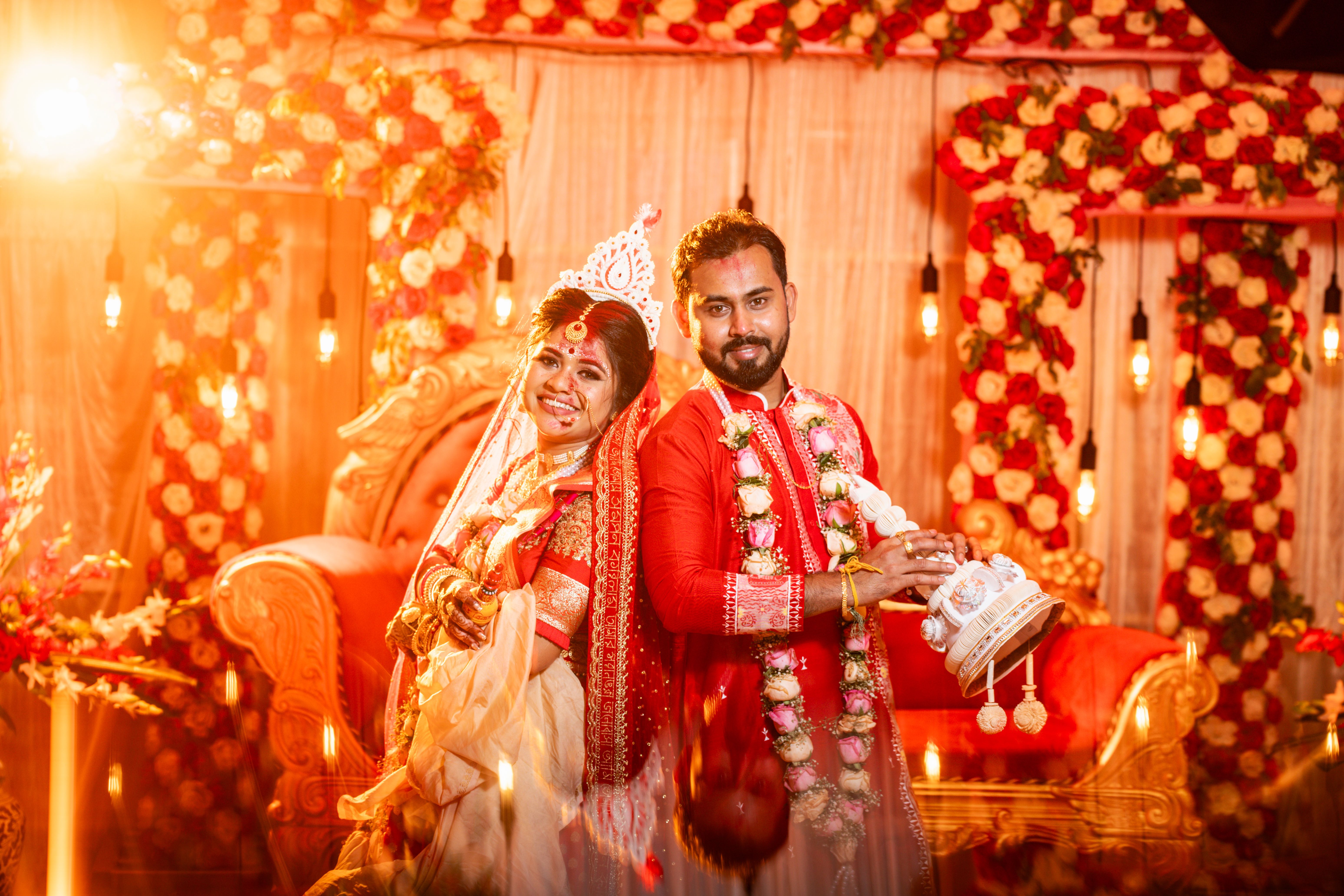 Joyful Bengali couple in traditional attire celebrating their wedding in Kolkata.