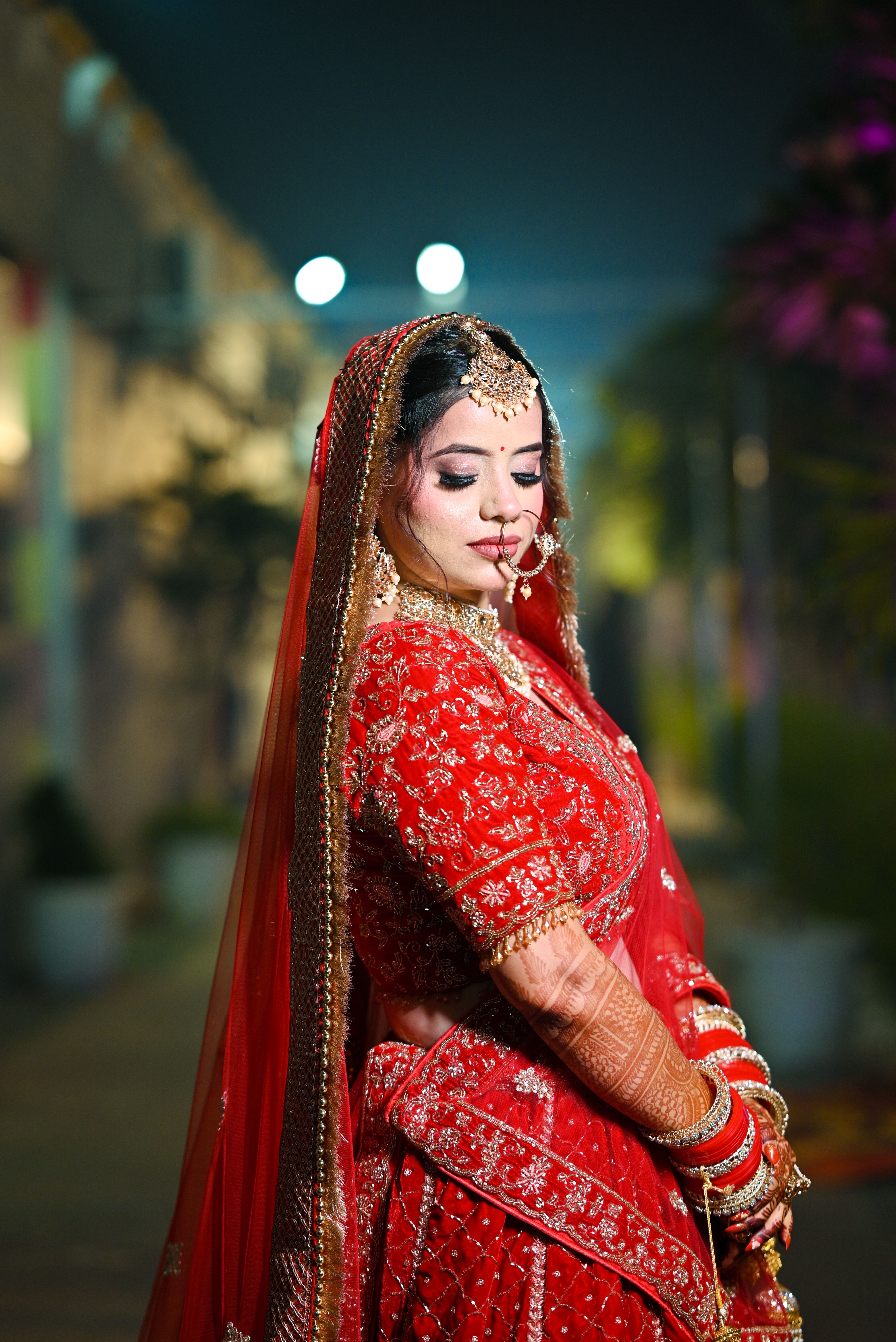 Stunning Indian bride in red lehenga adorned with intricate embroidery, captured in an elegant pose.