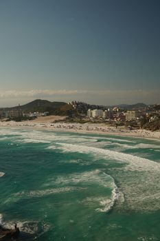 Captivating aerial view of Arraial do Cabo's beach with turquoise waters and a bustling shoreline in Brazil.