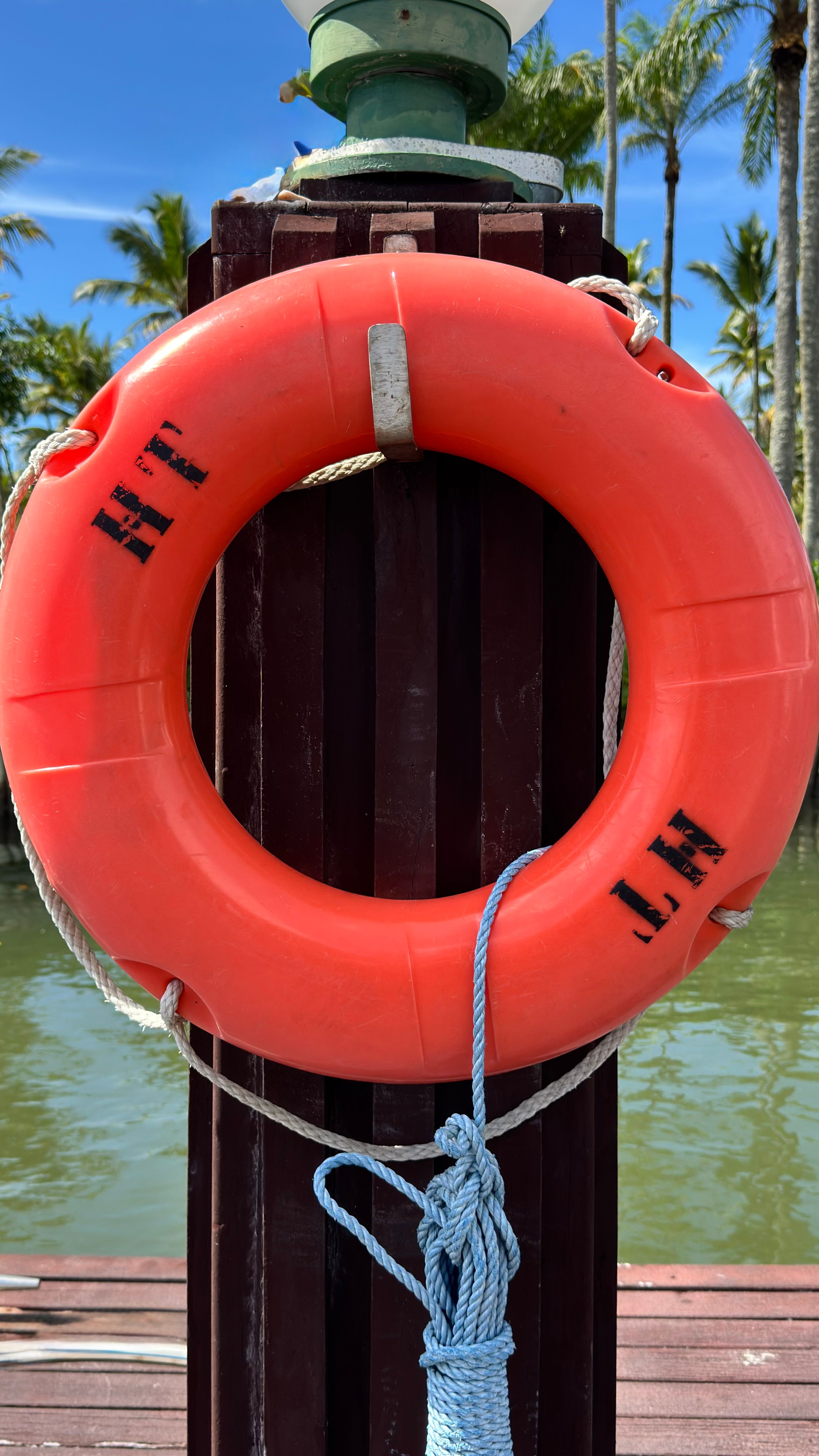 orange lifebuoy on wooden post by tropical lagoon