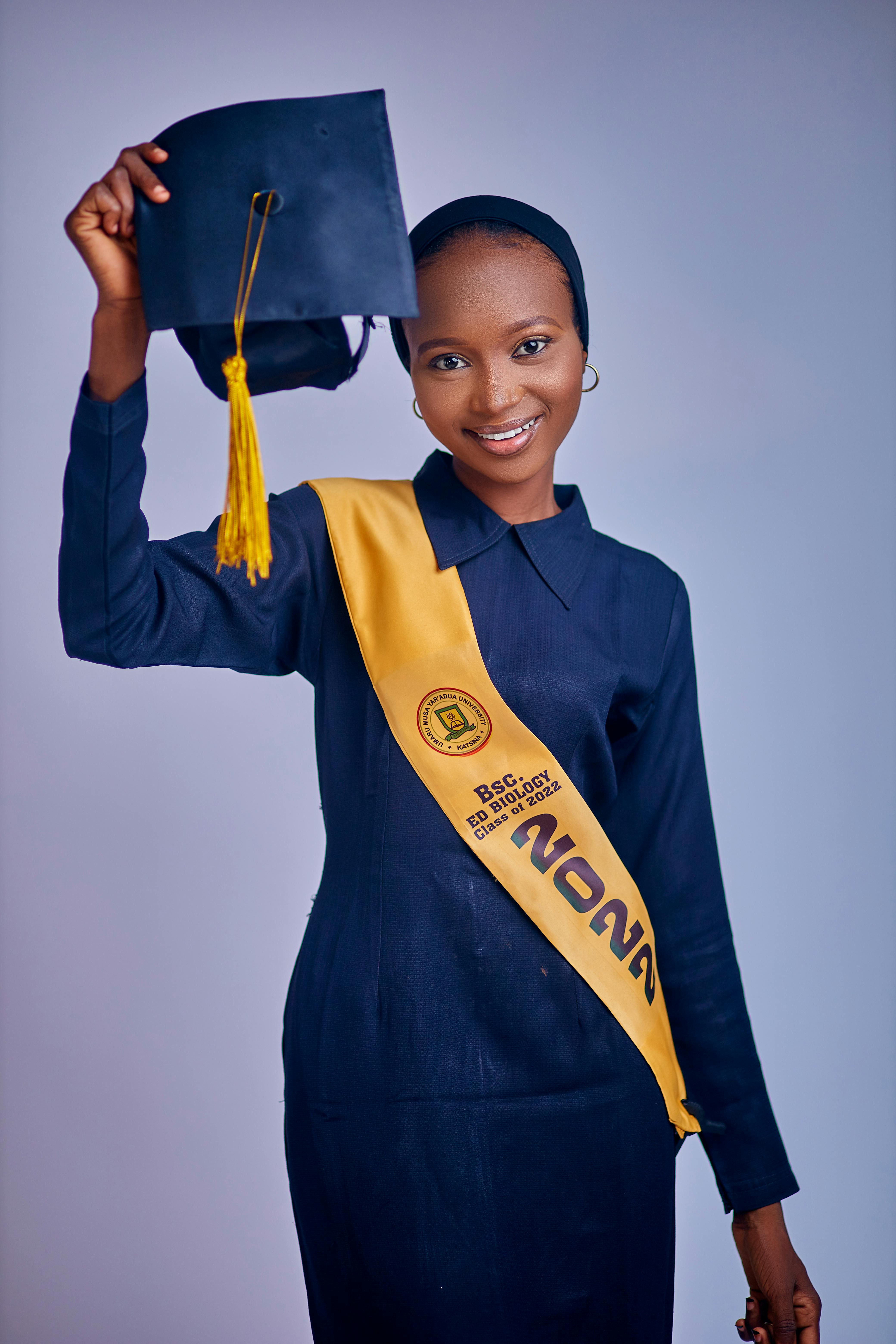Young woman holding a graduation cap with joy, celebrating academic achievement.