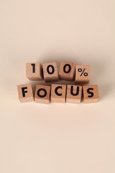 Wooden blocks spelling '100% FOCUS', symbolizing motivation and concentration.