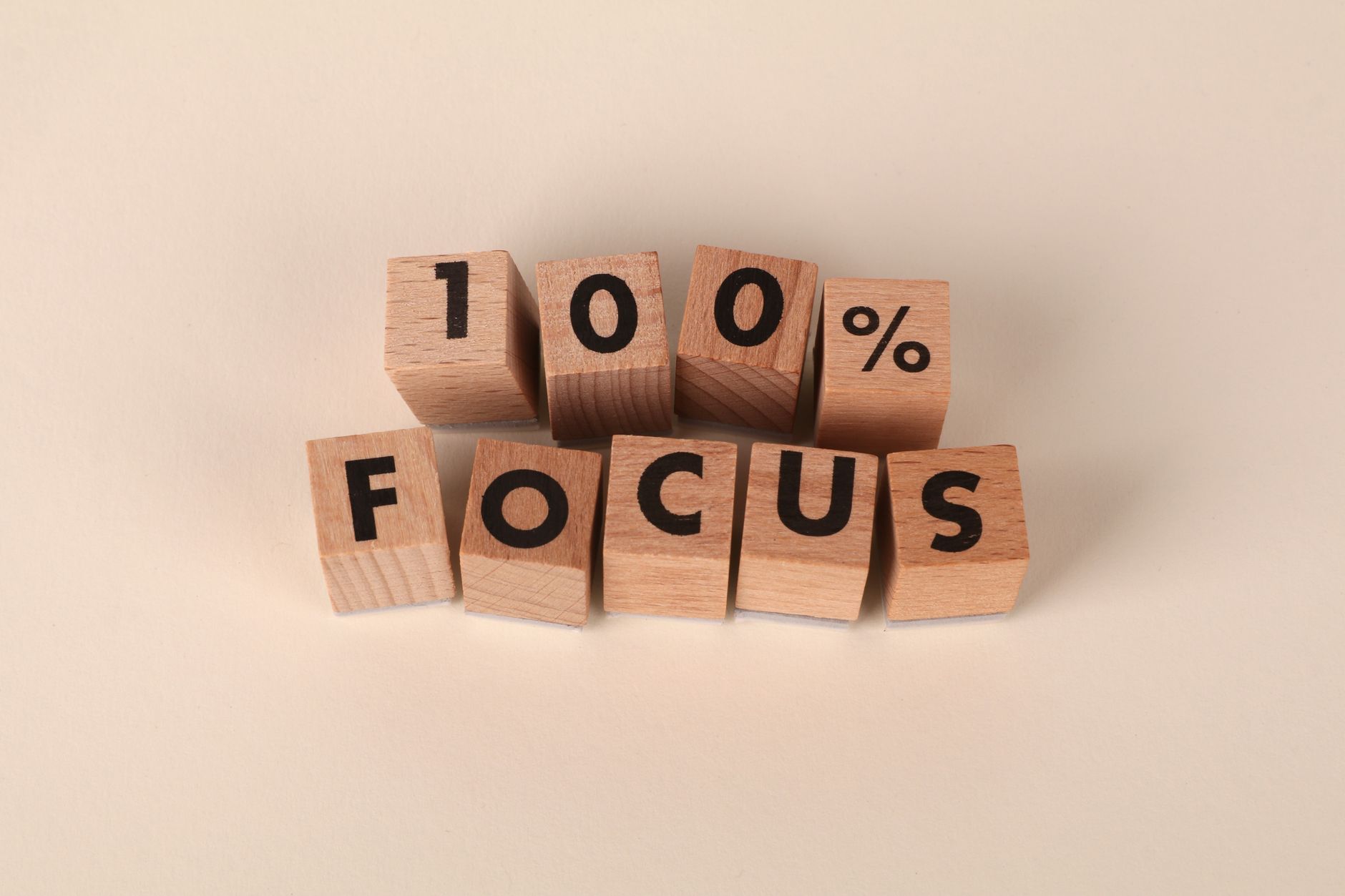 Wooden blocks arranged to spell '100% Focus', representing concentration and dedication.