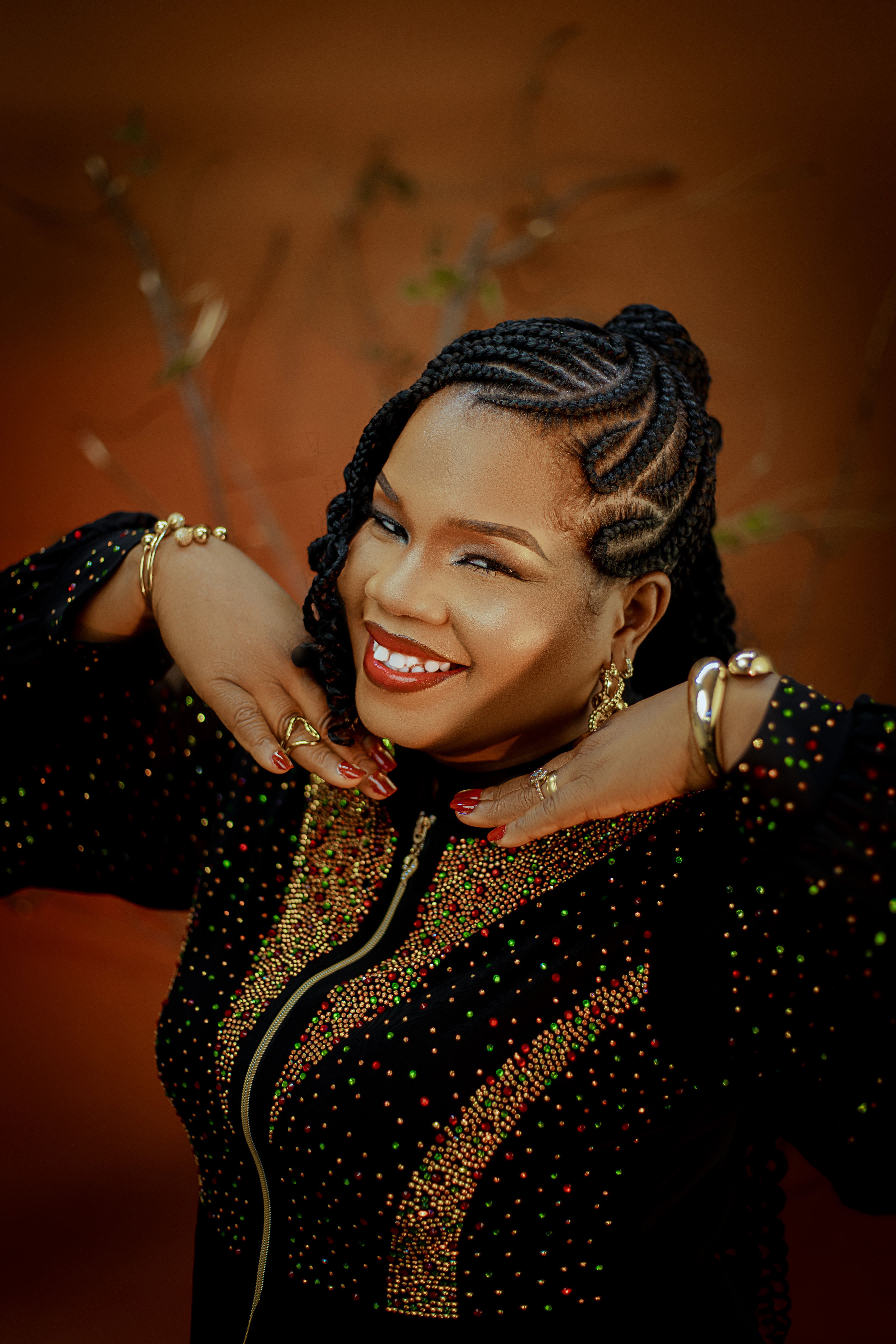 Beautiful woman with Afro-braids and colorful outfit smiling outdoors.