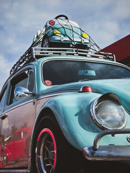 Vintage blue Beetle with a toy car on the roof, captured outdoors in daylight.