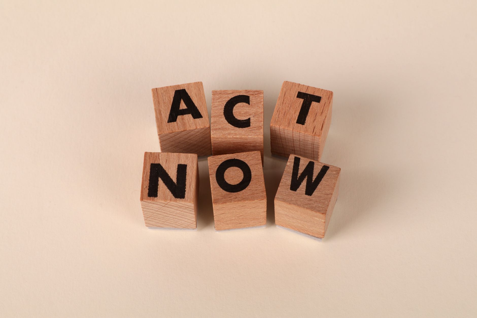 Wooden blocks with letters spelling 'ACT NOW', promoting urgency and motivation.