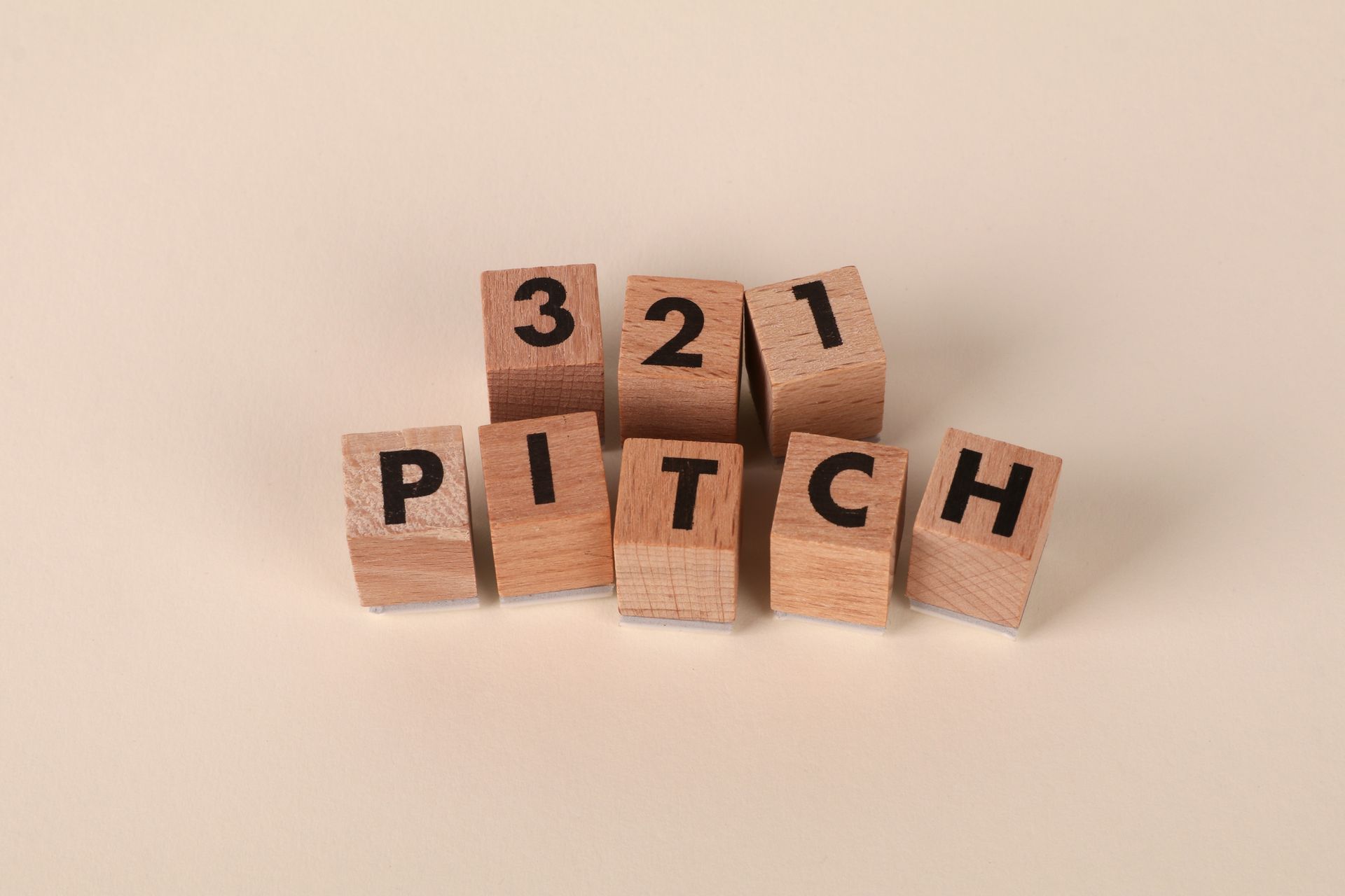 Wooden blocks arranged to spell '3-2-1 Pitch' on a beige background. Perfect for marketing themes.