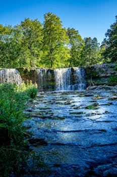 Experience the tranquil beauty of Keila waterfall in Estonia, captured on a sunny summer day.