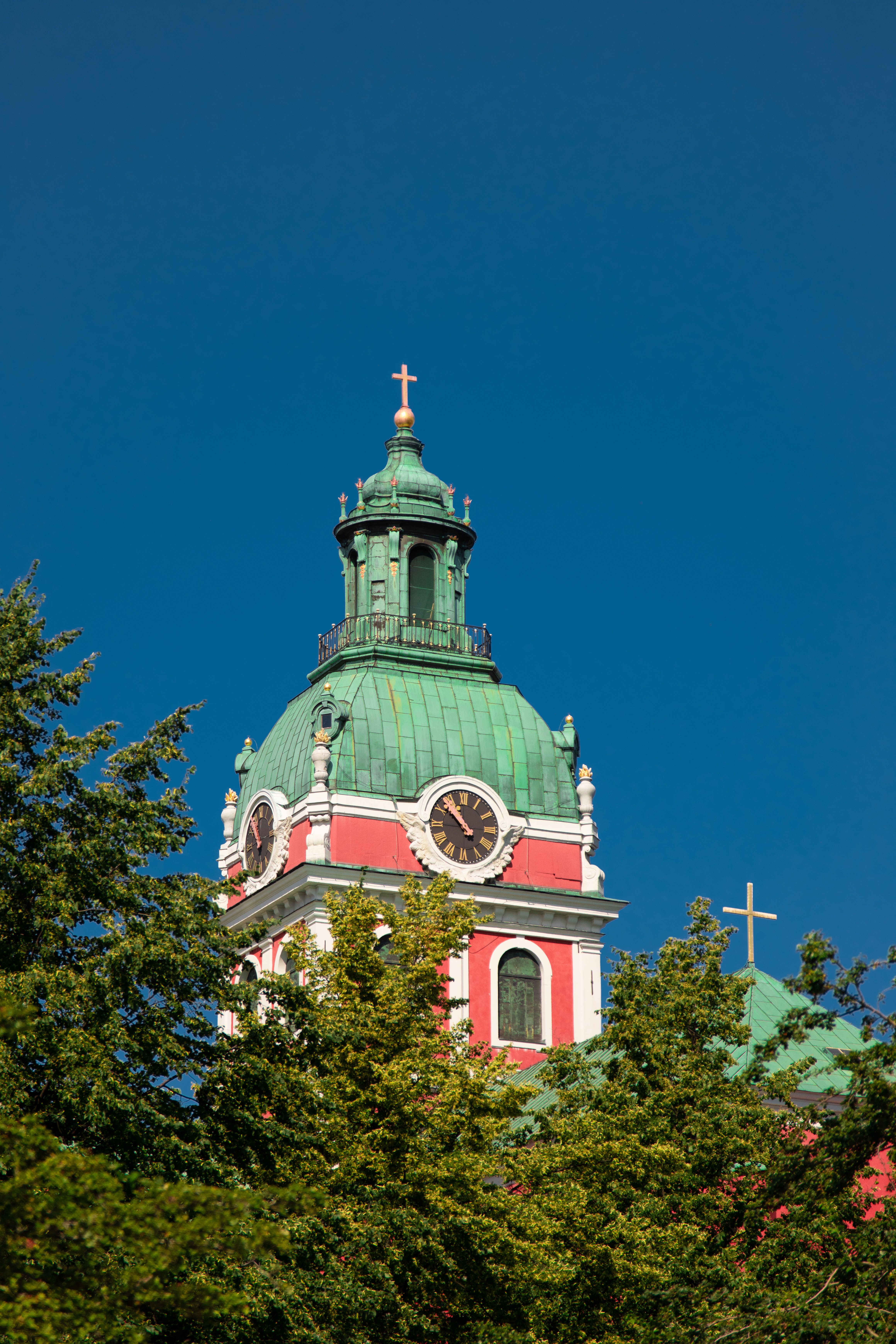 View of St. James's Church tower with a clock in Stockholm. Clear blue sky enhances the architecture.