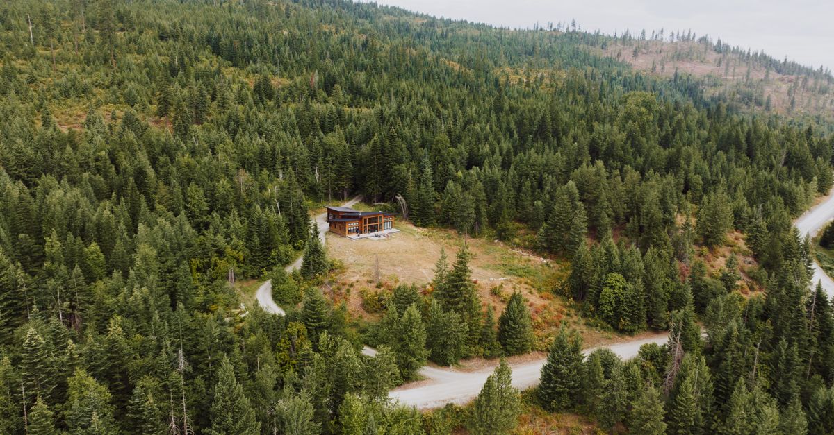 Aerial view of a remote cabin surrounded by dense forest in Priest River, Idaho.