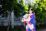 Young Graduate Holding Floral Bouquet Outdoors