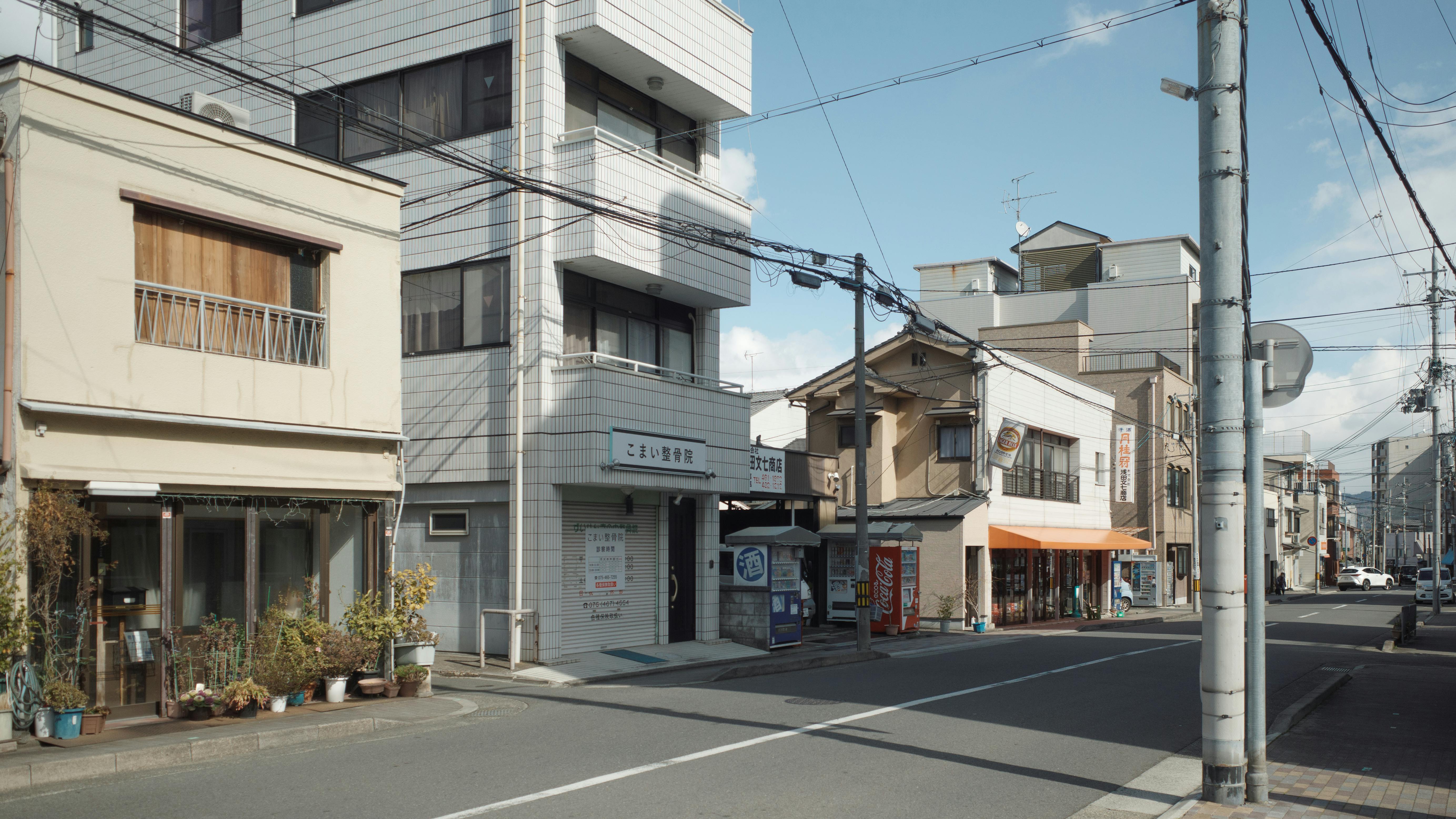 A picturesque street in Kyoto, showing traditional storefronts and urban architecture.