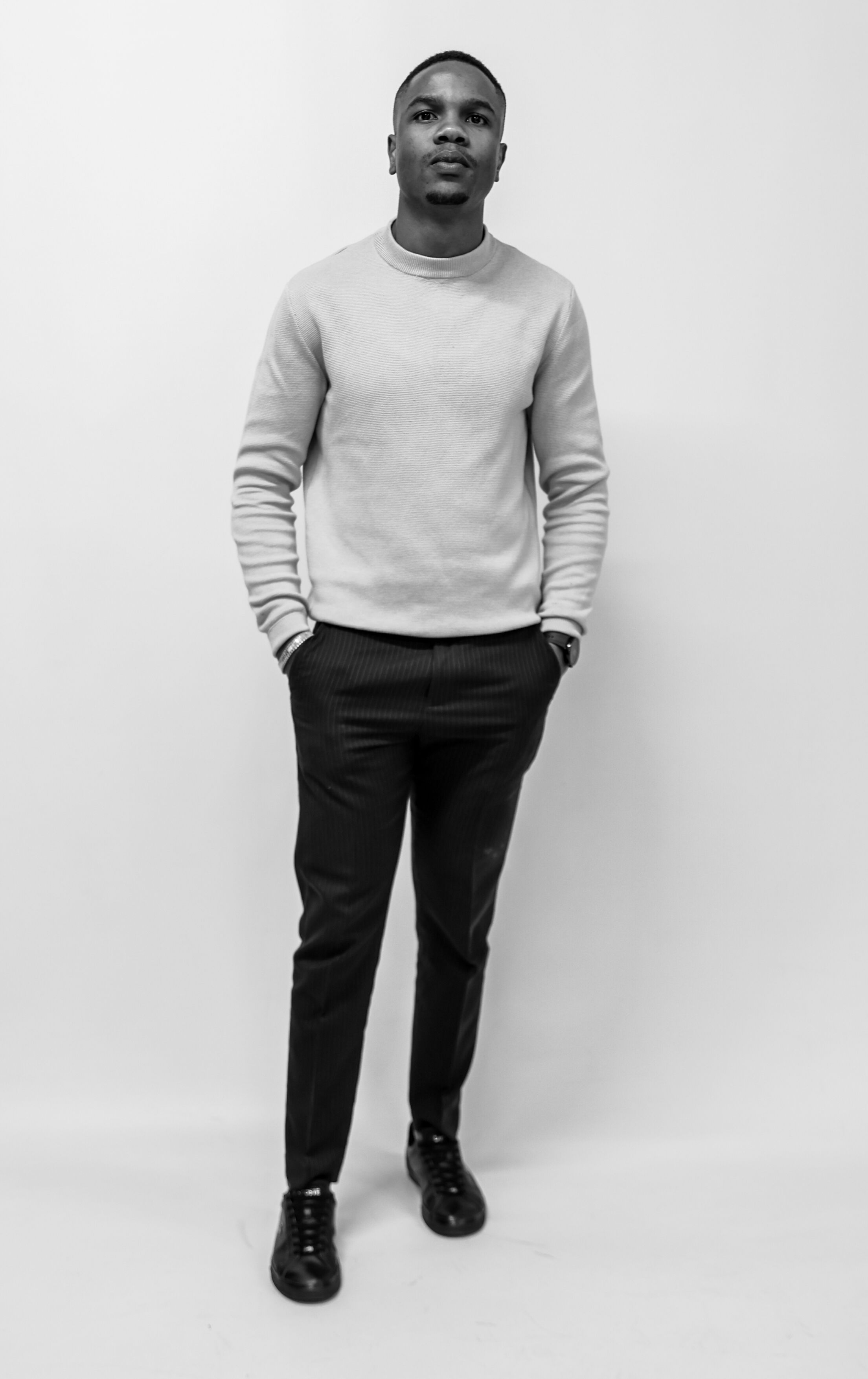 Black and white portrait of a stylish young man in casual wear, exuding confidence.