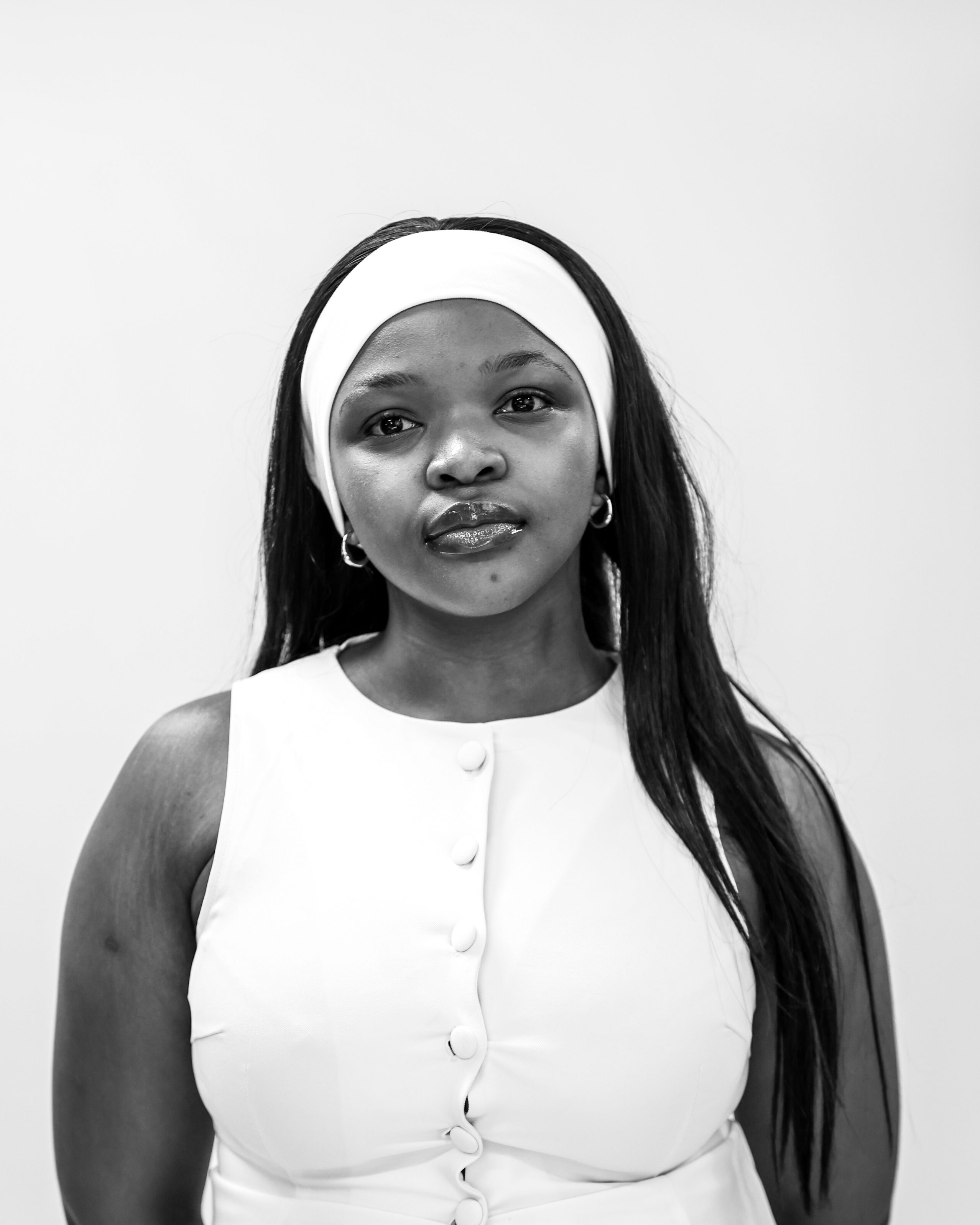 Sophisticated black and white photo of a woman in a white dress, showcasing elegance and calm.