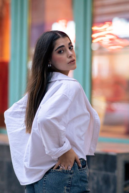 Free Elegant woman in white shirt poses confidently on a vibrant Tehran street. Stock Photo
