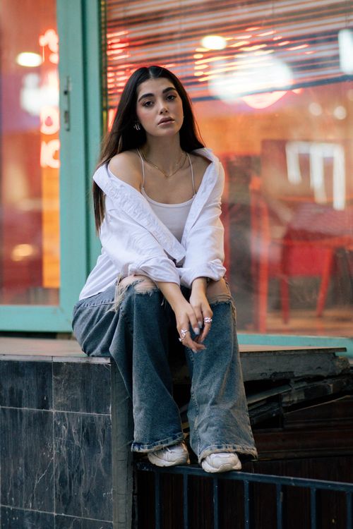 Free Stylish woman sitting outdoors in Tehran, showcasing modern fashion style. Stock Photo