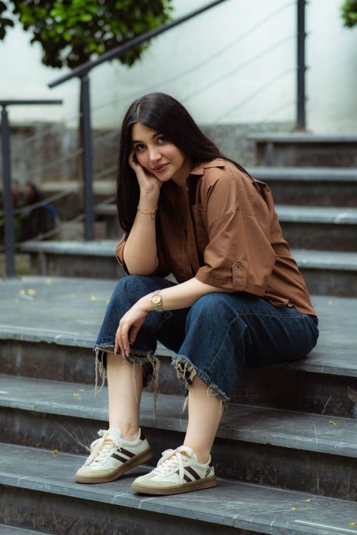Free A woman sitting on stairs in a casual outfit, expressing a relaxed mood. Stock Photo