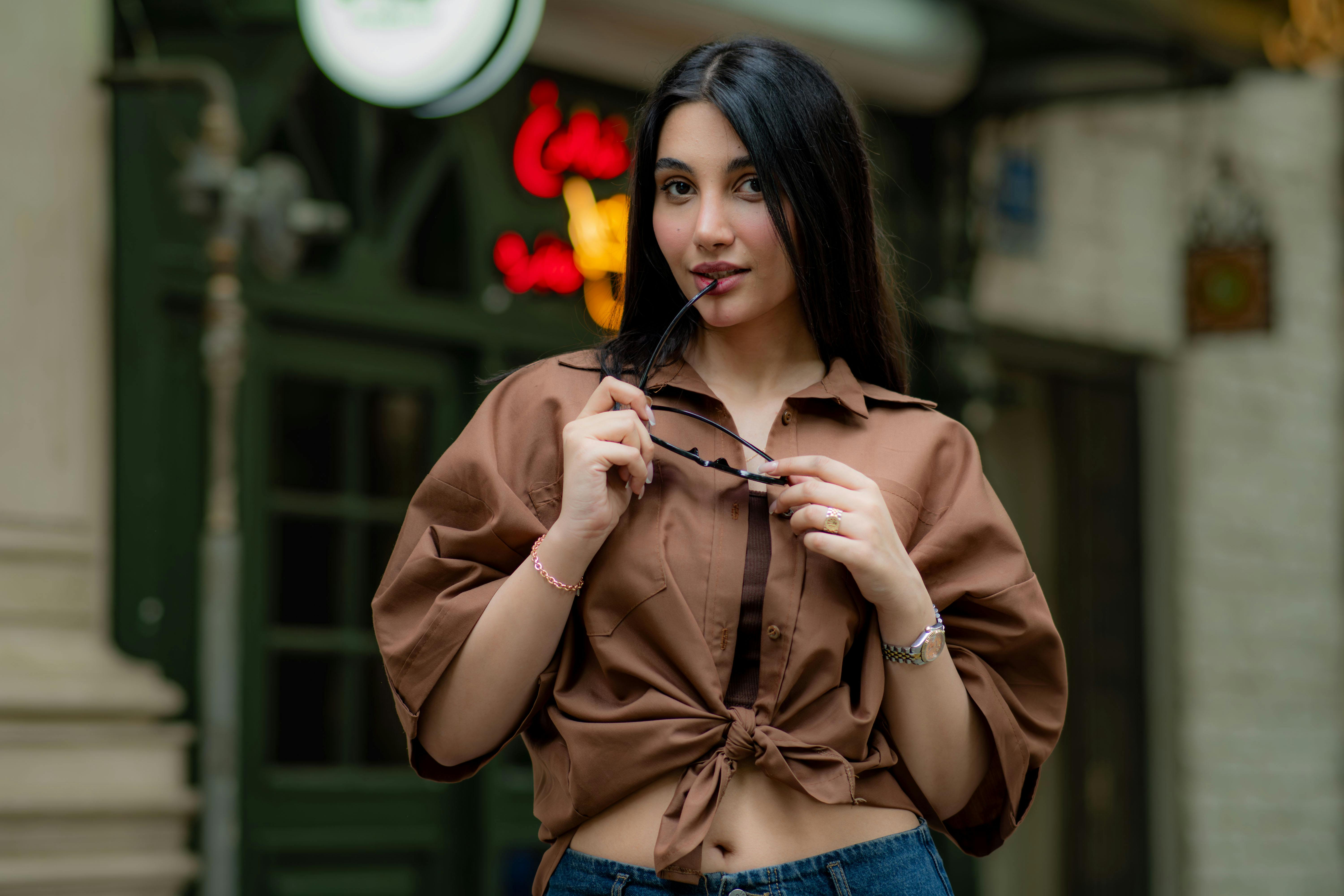 grátis Mulher estilosa, de camisa marrom, posa confiante com óculos de sol em uma rua em Teerã, Irã. Foto profissional