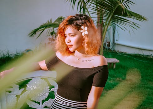 一位头发上插着花的女人坐在户外阳光下的长凳上