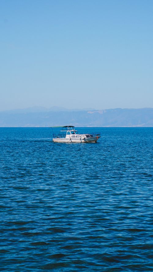 Free A solitary boat on the tranquil waters of Lake Ohrid under a clear blue sky. Stock Photo