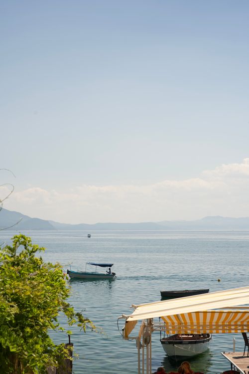 Free Tranquil lakeside scene with boats and striped awning on a sunny day. Stock Photo