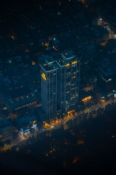 Aerial night view of a lit skyscraper amidst Seoul's cityscape.