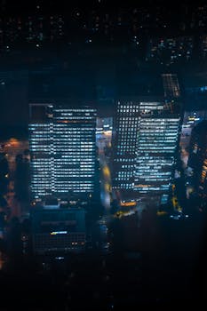 Stunning aerial view of illuminated skyscrapers in Seoul at night showcasing modern city life.