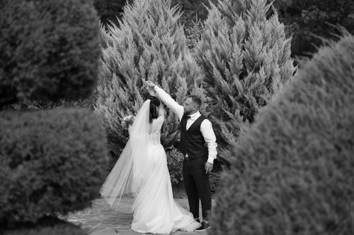 Free A romantic black and white photo of a couple dancing outdoors, surrounded by nature. Stock Photo