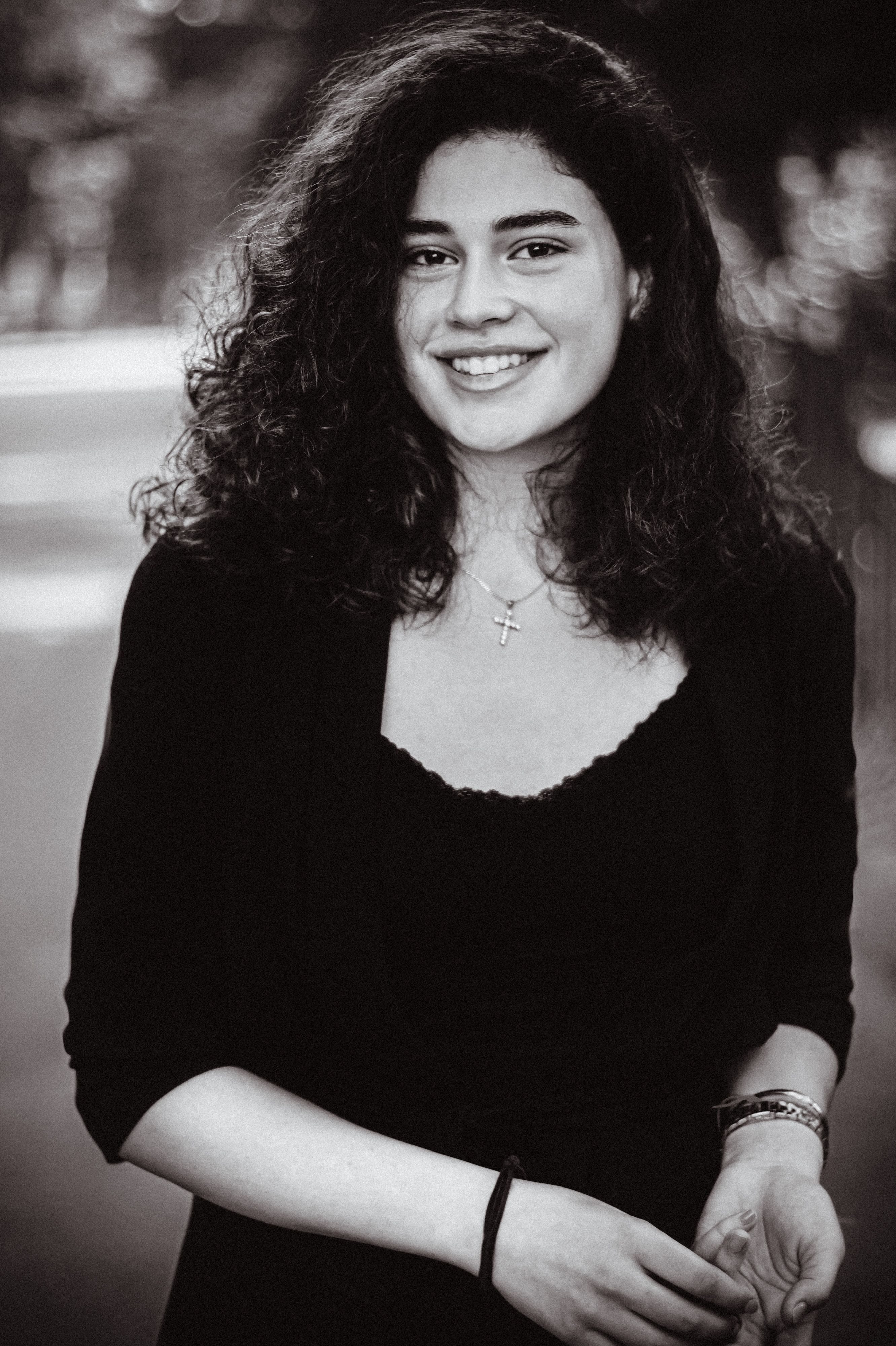 Artistic black and white portrait of a smiling woman outdoors in natural light.